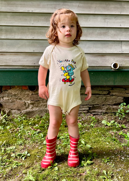 Child wearing a onesie with a cartoon design outdoors.