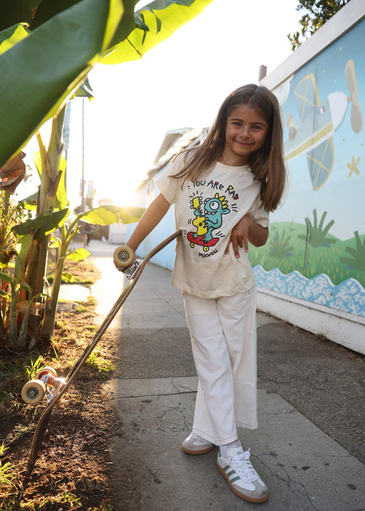 Young girl holding a skateboard with a mural in the background