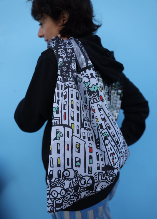 Person wearing a black jacket with a colorful cityscape design on a blue background