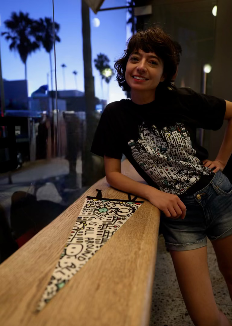 Person leaning against a wooden bench with a patterned design in an indoor setting.